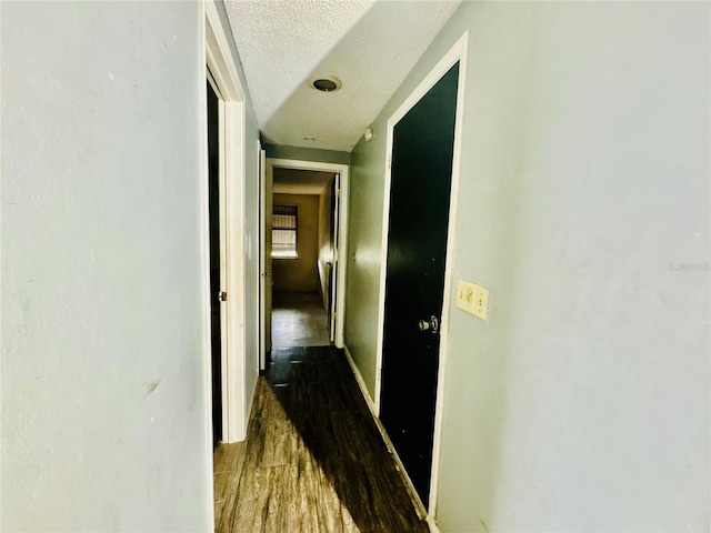 hall with a textured ceiling and wood finished floors