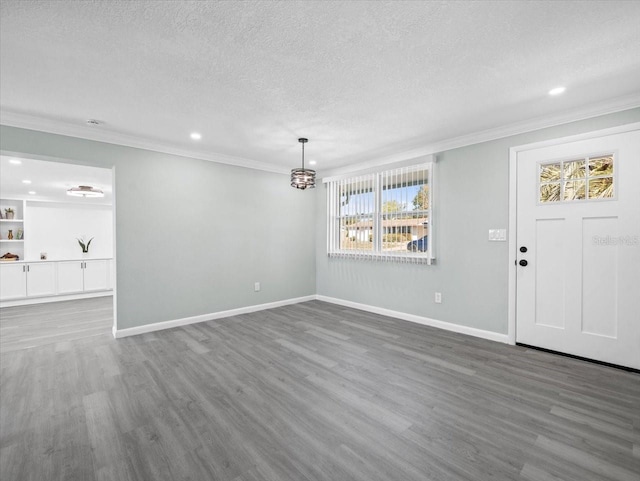 interior space featuring crown molding, a textured ceiling, baseboards, and wood finished floors