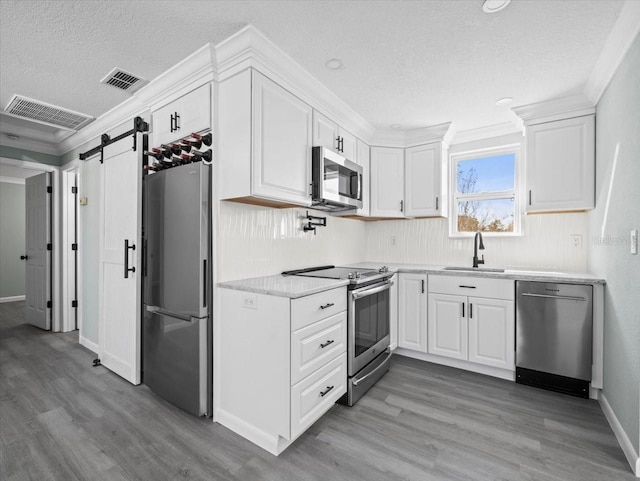 kitchen featuring stainless steel appliances, visible vents, a sink, and a barn door