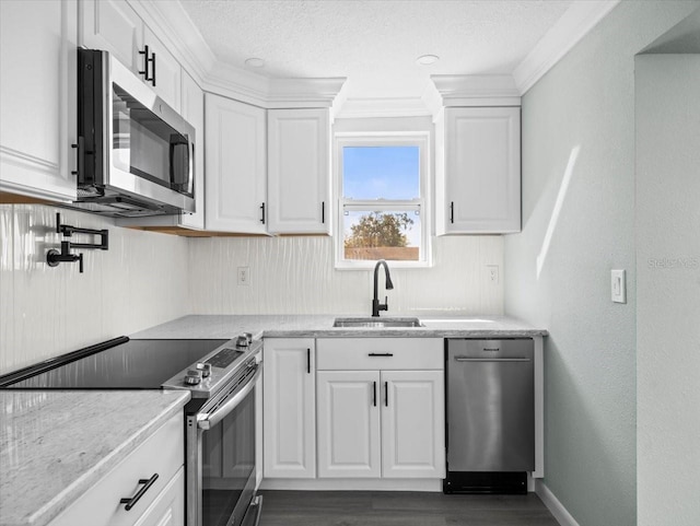 kitchen featuring dark wood finished floors, stainless steel appliances, white cabinets, a sink, and a textured ceiling