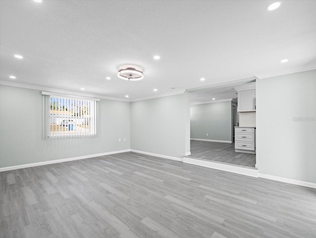 interior space with ornamental molding, light wood-type flooring, and baseboards