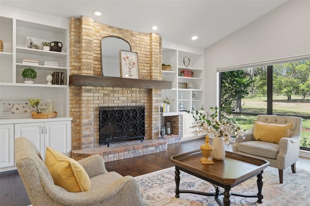 living area featuring built in features, lofted ceiling, a brick fireplace, and wood finished floors