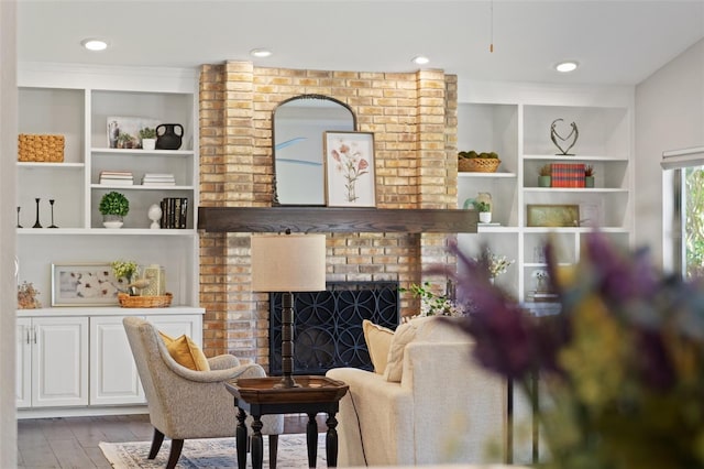 living area featuring recessed lighting, a fireplace, built in shelves, and wood finished floors