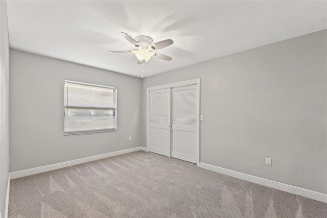 unfurnished bedroom with a closet, baseboards, carpet floors, and ceiling fan