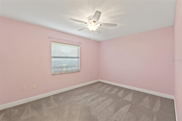 carpeted spare room featuring baseboards and ceiling fan