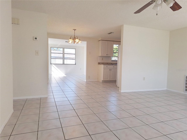 spare room featuring a healthy amount of sunlight, a textured ceiling, and light tile patterned flooring