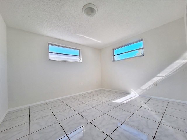 empty room with baseboards, a textured ceiling, and a healthy amount of sunlight