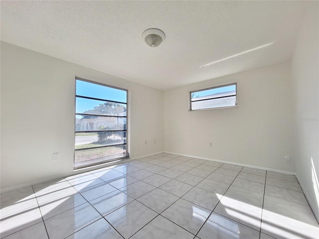 spare room with baseboards, a textured ceiling, and light tile patterned flooring