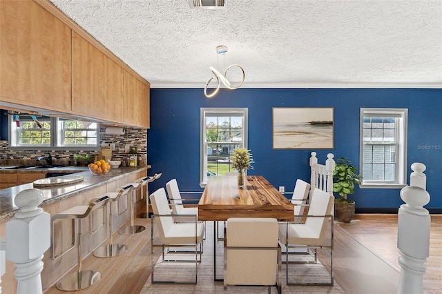 dining room with a notable chandelier, a textured ceiling, visible vents, and wood finished floors