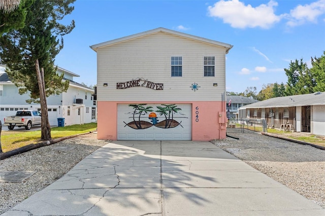 view of front of house featuring concrete driveway, an attached garage, and fence