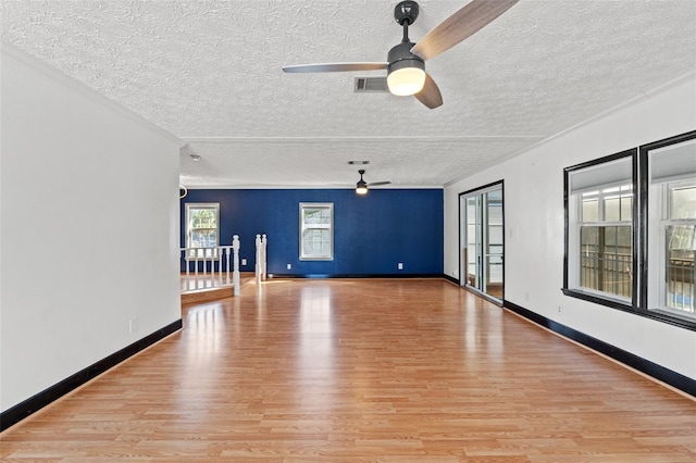 spare room featuring a textured ceiling, light wood-style floors, visible vents, and baseboards