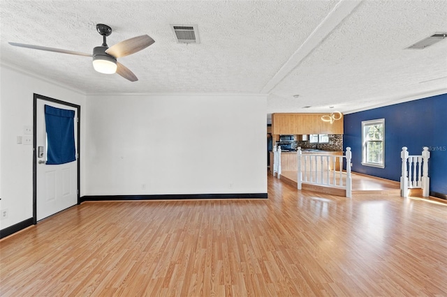 empty room with ceiling fan, visible vents, baseboards, and wood finished floors