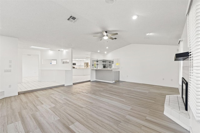 unfurnished living room with light wood finished floors, a brick fireplace, visible vents, and a ceiling fan