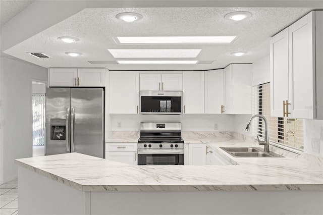 kitchen with visible vents, appliances with stainless steel finishes, a peninsula, white cabinetry, and a sink