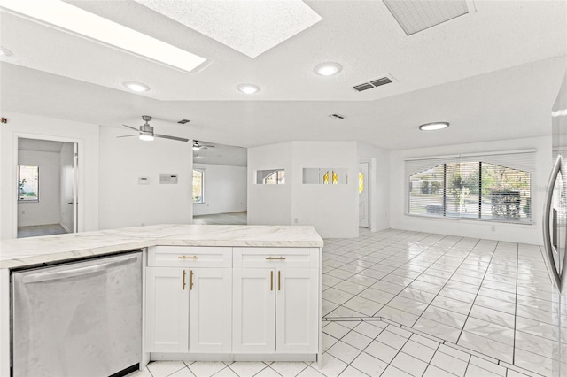 kitchen with white cabinets, a skylight, open floor plan, and stainless steel dishwasher