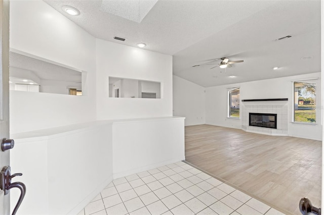 interior space with a skylight, ceiling fan, visible vents, and a tiled fireplace