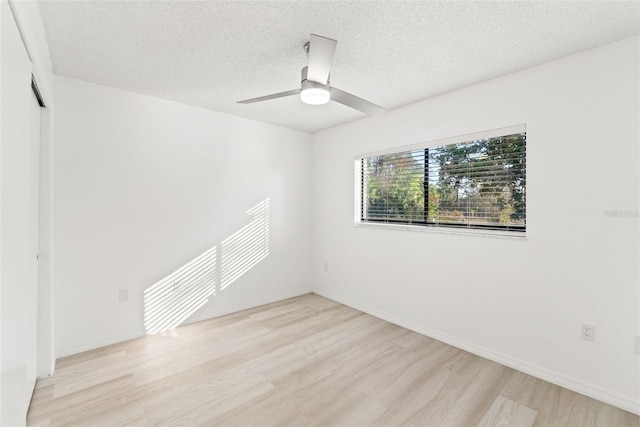 spare room featuring a textured ceiling, ceiling fan, wood finished floors, and baseboards