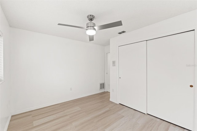 unfurnished bedroom featuring light wood-type flooring, a closet, visible vents, and baseboards