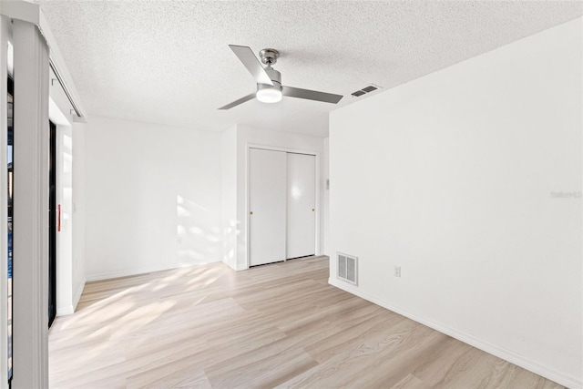 unfurnished bedroom with light wood-type flooring, a closet, visible vents, and a textured ceiling