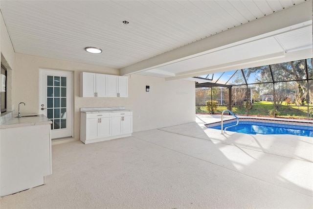 outdoor pool featuring glass enclosure, a patio area, and a sink