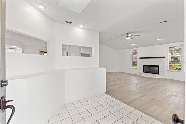 1011 Altoona Ave, Spring Hill, FL 34609 - unfurnished living room featuring healthy amount of natural light, light tile patterned flooring, ceiling fan, a textured ceiling, and a tile fireplace