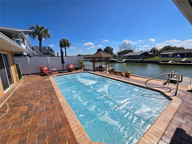 view of swimming pool featuring a water view, fence, a gazebo, and a patio