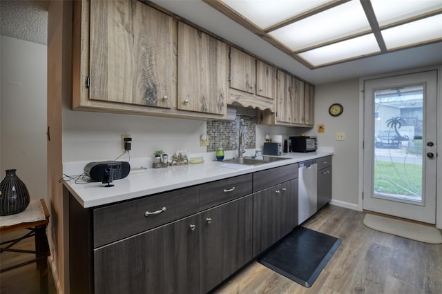 kitchen featuring a sink, baseboards, light countertops, stainless steel dishwasher, and light wood-type flooring