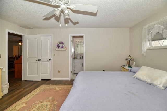 bedroom featuring connected bathroom, dark wood finished floors, a textured ceiling, and ceiling fan