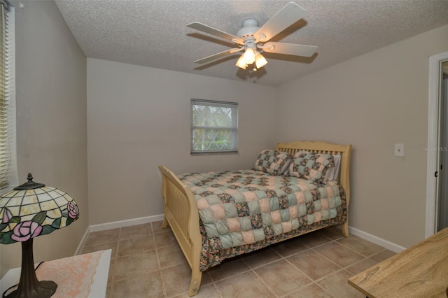 tiled bedroom featuring a textured ceiling, a ceiling fan, and baseboards