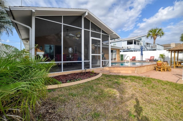 back of property with a lawn, a fenced in pool, a sunroom, fence, and a patio area