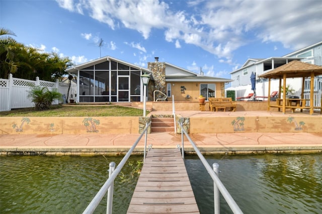 dock area with a patio, a water view, fence, and a gazebo