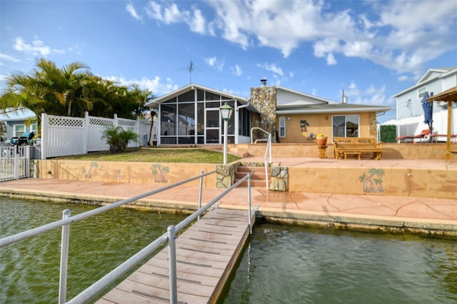 view of dock featuring a water view, a patio area, and fence