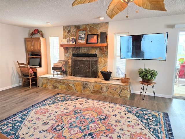 living area with ceiling fan, a textured ceiling, and wood finished floors
