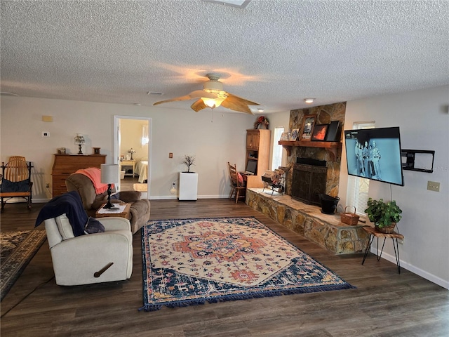 living area featuring baseboards, a fireplace, a ceiling fan, and a textured ceiling