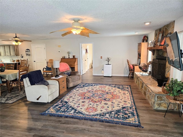 living area featuring a textured ceiling, ceiling fan, and a fireplace