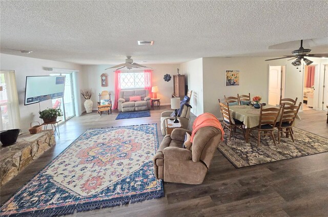 living area with visible vents, a textured ceiling, ceiling fan, and wood finished floors