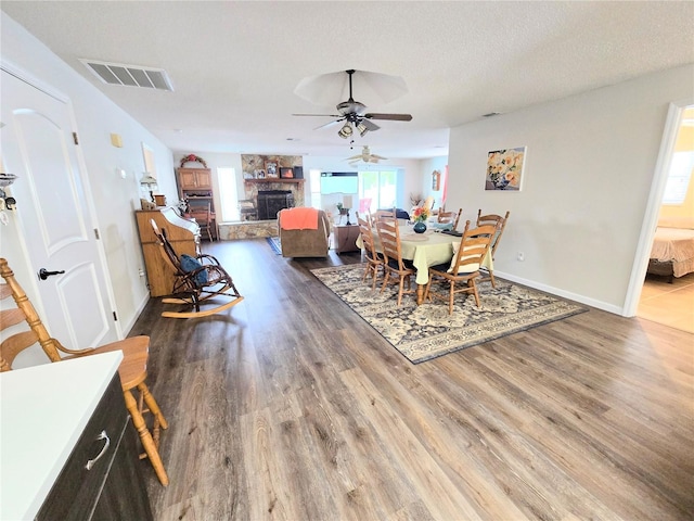 dining space featuring ceiling fan, visible vents, wood finished floors, and a fireplace