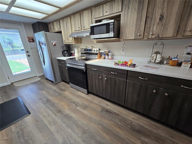 kitchen featuring under cabinet range hood, stainless steel appliances, light wood-style flooring, and light countertops