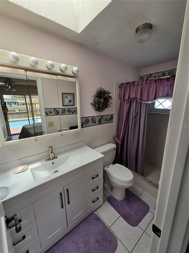 bathroom featuring tile walls, a stall shower, vanity, tile patterned floors, and toilet