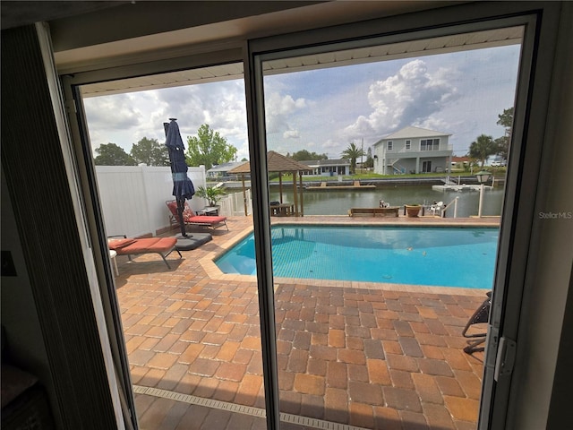 view of pool with fence, a fenced in pool, a water view, and a patio area