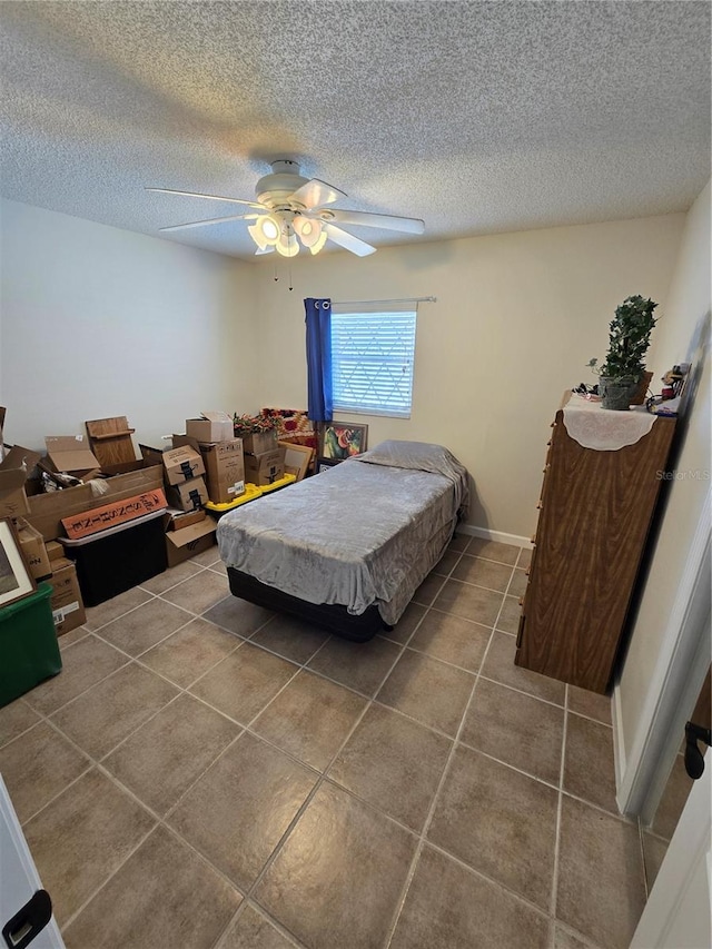 tiled bedroom with a ceiling fan and a textured ceiling