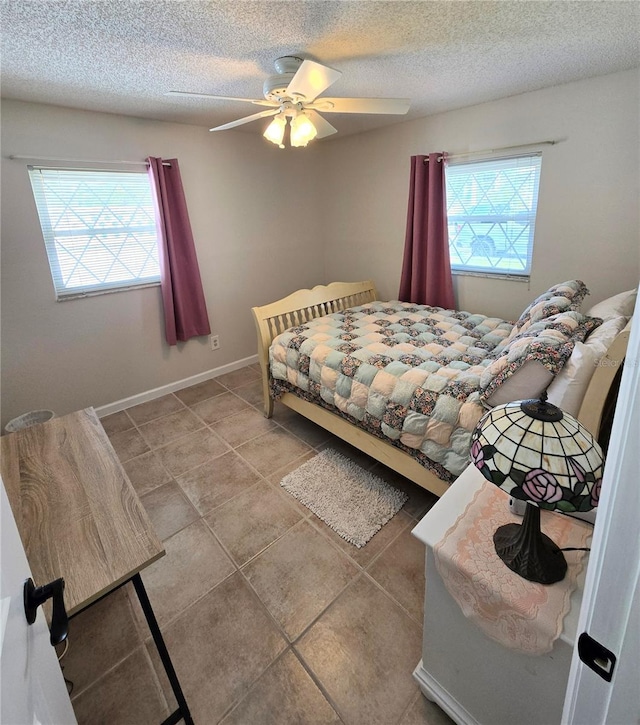 bedroom featuring baseboards, tile patterned flooring, a ceiling fan, and a textured ceiling