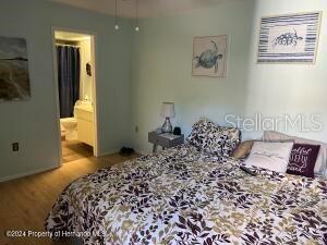 bedroom with wood finished floors and connected bathroom