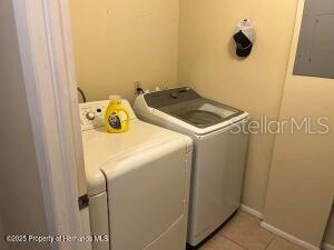 clothes washing area with light tile patterned floors, laundry area, independent washer and dryer, and electric panel