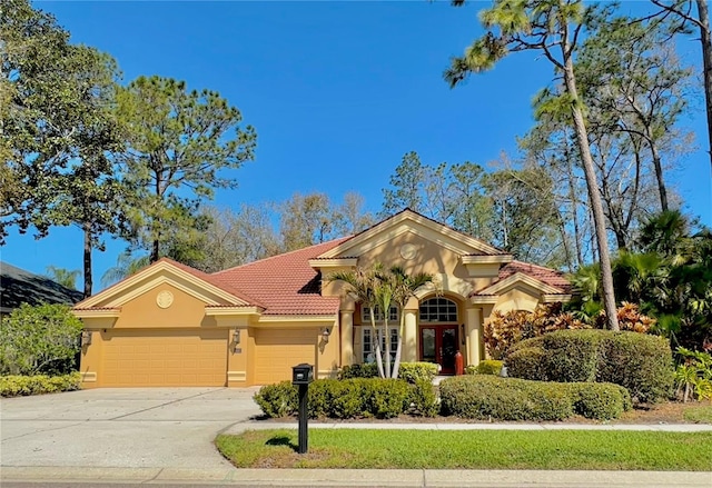 mediterranean / spanish-style house with an attached garage, a tile roof, driveway, french doors, and stucco siding