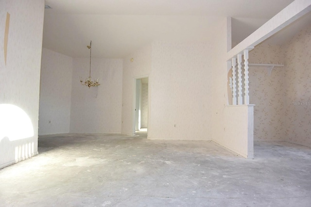 unfurnished room with concrete flooring and a notable chandelier