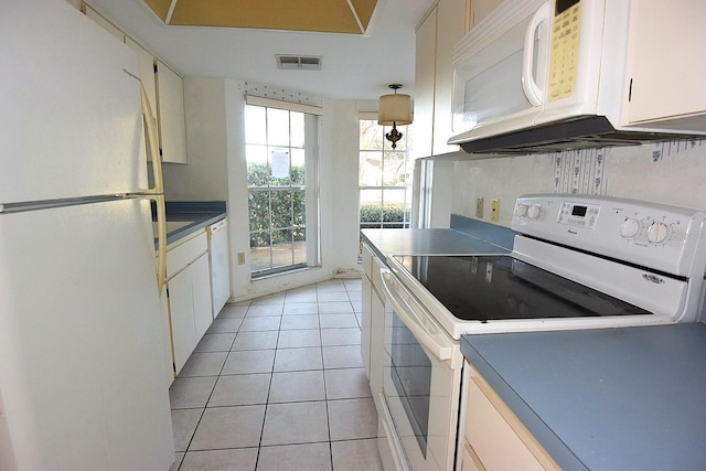 kitchen featuring white appliances, visible vents, dark countertops, white cabinetry, and light tile patterned flooring