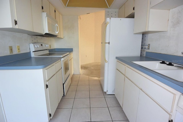 kitchen with white appliances, white cabinets, a sink, and light tile patterned flooring