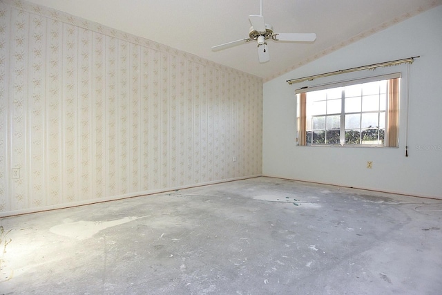 spare room featuring concrete flooring, vaulted ceiling, baseboards, and wallpapered walls