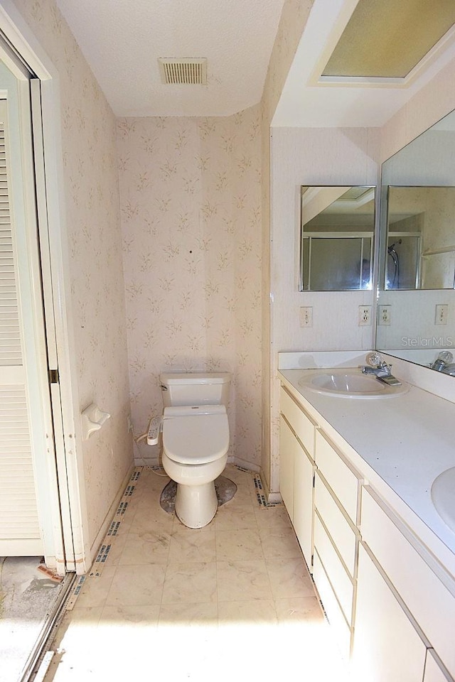 bathroom with visible vents, a sink, toilet, and wallpapered walls